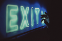 Anonymous person near neon exit sign Free Stock Photo