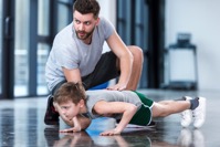 Boy doing push ups with coach at fitness center 2021 08 29 10 47 11 utc