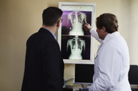 Doctor Pointing X ray Result Beside Man Wearing Black Suit Free Stock Photo