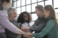 Happy multiracial coworkers uniting hands after making decision Free Stock Photo