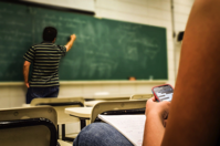 Man in Black and White Polo Shirt Beside Writing Board Free Stock Photo