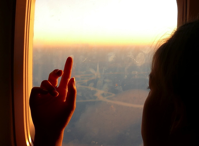 kid looking out window of a plane.