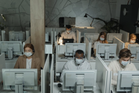 PEople working at computers with masks.
