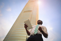 Businessman holding tablet in front of skyscraper