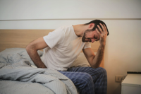 Young man in sleepwear suffering from headache in morning Free Stock Photo