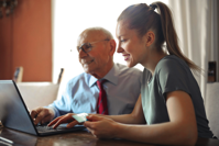 Young woman helping senior man with payment on Internet using laptop Free Stock Photo